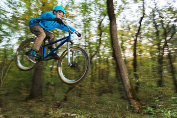 Naklejka premium a young guy in a helmet flies landed on a bicycle after jumping from a kicker