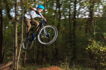 a young guy in a helmet flies on a bicycle after jumping from a kicker