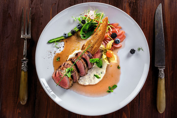Gourmet medium rare meat steak with sauce and fresh salad. Healthy meal made of meat fillet and fresh vegetables on a rustic table. Top view.