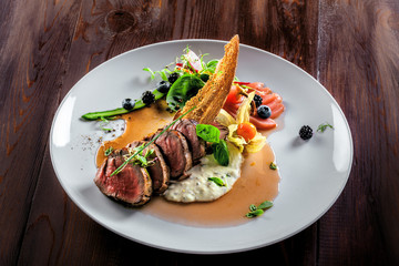Tasty medium rare meat steak with sauce and salad. Gourmet meal made of meat fillet and vegetables. Delicious healthy food.