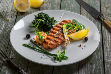 Delicious grilled salmon fish steak with vegetable salad. Healthy meal for lunch made of seafood fish and vegetables on a wooden table.
