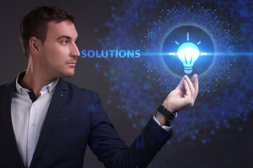 Business, Technology, Internet and network concept. Young businessman working on a virtual screen of the future and sees the inscription: Solutions