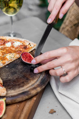 Close up female hands cutting fig with knife
