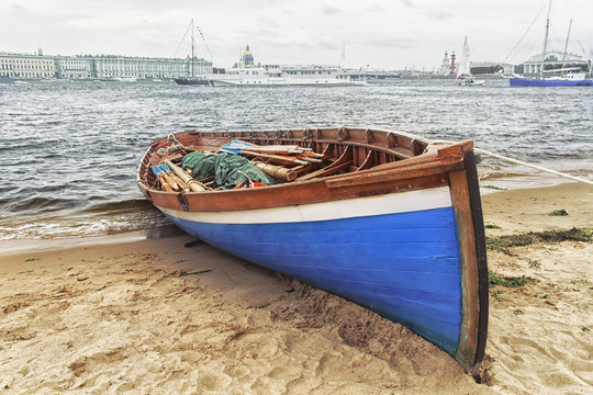 Blue wooden sailing boat with oars at the banks of river