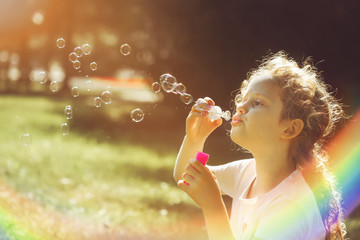 Little girl blowing soap bubbles.