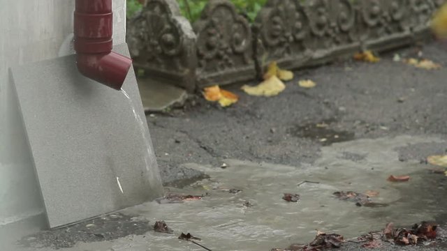 Rain water flowing from drain pipe closeup
