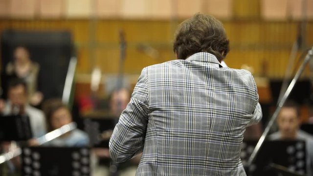 The conductor conducts an orchestra in the Studio. The view from the back