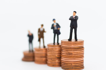 Miniature people: Business man standing on stack of coin using as background Money and financial concepts.