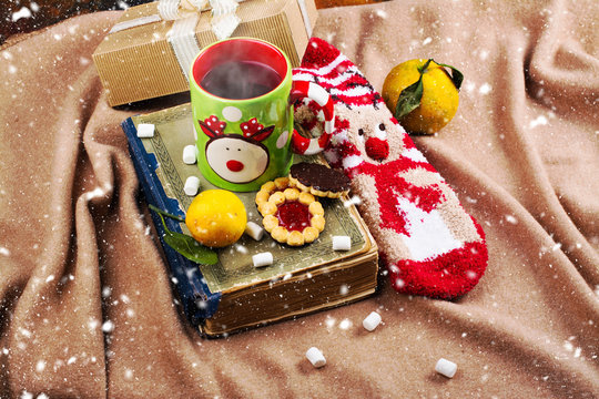Cozy Christmas evening set with vintage book, hot mulled wine, socks and cookies on warm blanket. Copy space