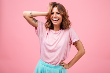 Cheerful young woman isolated over pink background posing