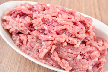 ground pork in a white plate on wooden table