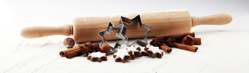 Christmas baking ingredients and tolls for dough preparation. Flour, rolling pin and cookies and spices.