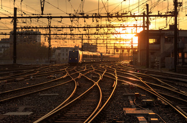 Fototapeta na wymiar A train on the railroad tracks during a beautiful sunrise. Lyon, France.