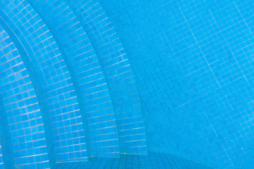 Water on blue tiled swimming pool with stairs background.
