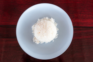 Authentic freshly cook Thai jasmine rice on plastic plate on red wooden dinner table top down view.