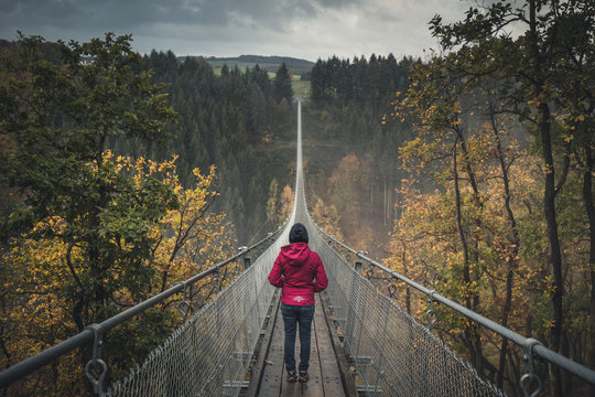 Young woman on Geierlay Supsension Bridge, Germany, on a cold autumn morning