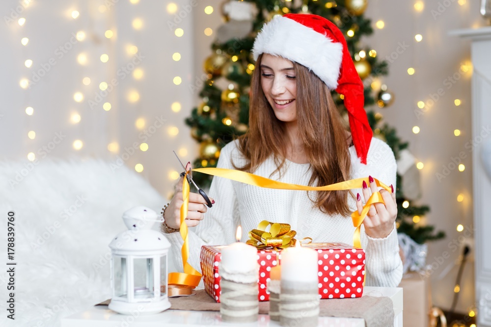 Wall mural A happy cheerful girl celebrating new year wrapping presents