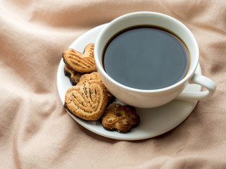 Cup of coffee with homemade cookies on the bed blankets