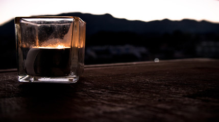 Lus de una vela en un cuenco de cristal y de fondo un paisaje de montaña