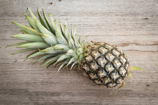 Pineapple on wooden background. Top view with dark vignette. Tropical fruit.