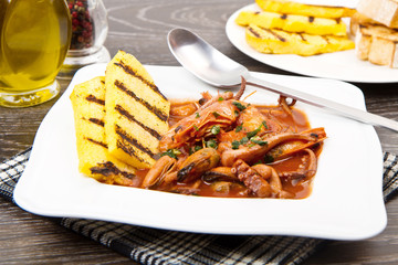 fish soup with grilled polenta on white dish