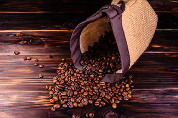 Roasted coffee beans in sack on wooden table