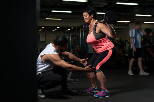 Fitness Coach Assisting His Female Client In Gym