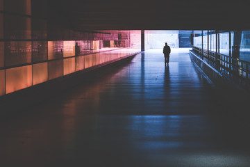 silhouette of a person walking in a dark tunnel