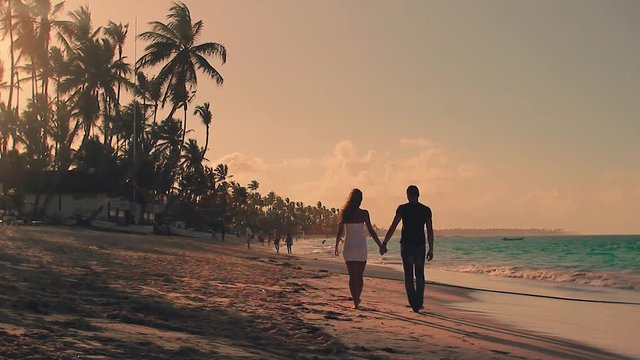 Couple Walking Along Summer Beach at Sunset