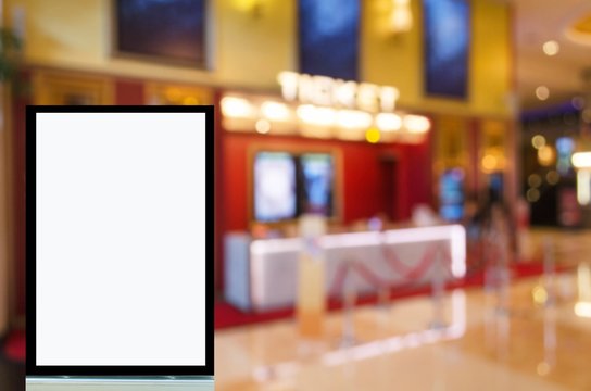 vertical advertising billboard or blank showcase light box for your text message or media content with blurred image of ticket sales counter at movie theater, commercial and marketing concept