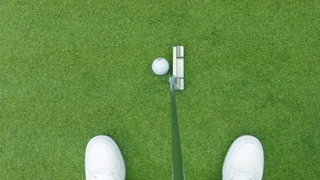 Close-up of golfer using putter to sink short putt into hole