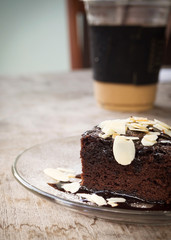 Closeup homemade brownie on glass plate. Served with almond sliced topping and chocolate sauce. Sweet and moist dessert.