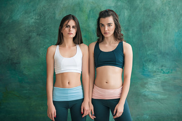 Two young sporty women posing at gym.