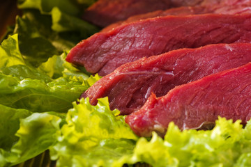 Meat with lettuce on the table cut into pieces, close-up