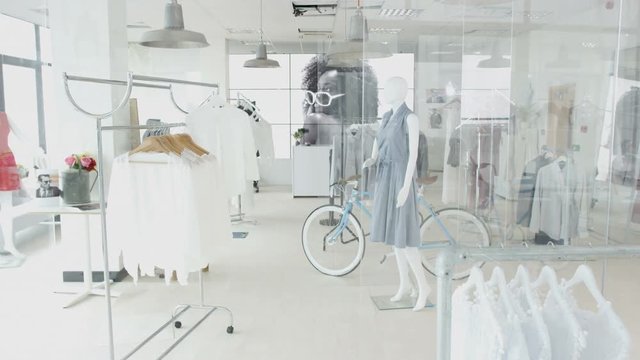 Interior of a fashionable women's clothing store with clothes racks and mannequins.