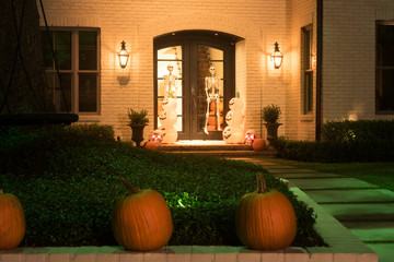 The house is decorated for Halloween: pumpkins are real and artificial, skeletons on the doors. Night