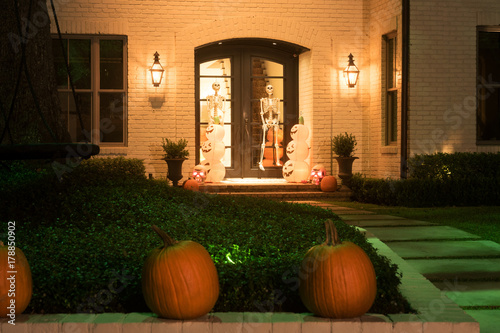 The house is decorated for Halloween: pumpkins are real and artificial, skeletons on the doors. Night