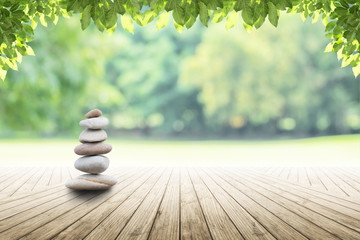 Obraz premium zen stones on empty wooden with green leaf in the garden background blurred and . Concept relaxation, zen, spring. 