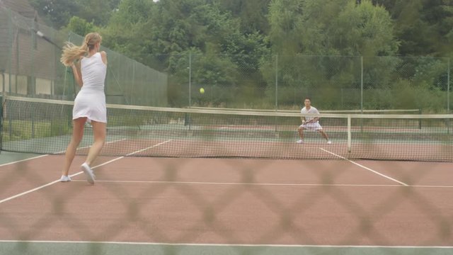  Male & female tennis players enjoying a game on outdoor court in the summer