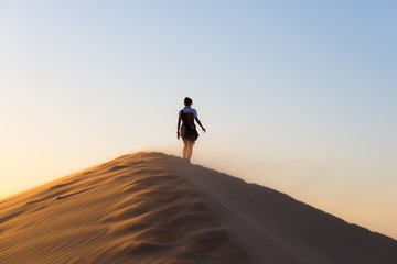 Fototapeta na wymiar Tourist walking on the sand dunes at Sossusvlei, Namib desert, Namib Naukluft National Park, Namibia. Traveling people, adventure and vacations in Africa.
