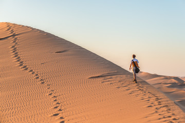 Tourist walking on the sand dunes at Sossusvlei, Namib desert, Namib Naukluft National Park, Namibia. Traveling people, adventure and vacations in Africa.