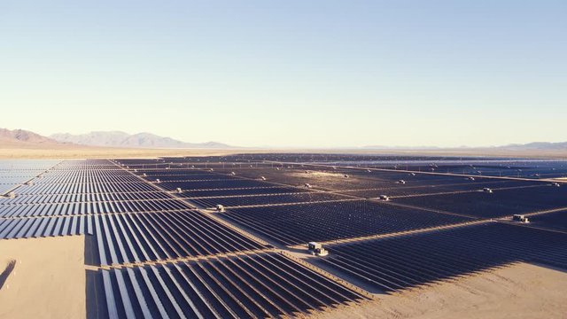 Aerial view flying over large industrial solar energy farm in desert 