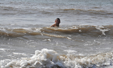 A young man swims and having fun in the sea with a naked torso