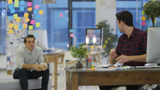  Young designers fooling around & throwing rolled up papers in creative office