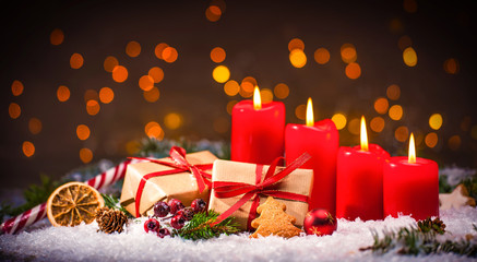 Advent decoration with four burning candles and gift boxes
