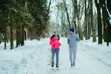Fototapeta na wymiar Young couple running during winter at park