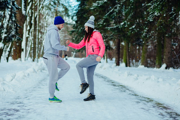 Fototapeta na wymiar Fitness couple doing stretching exercise before running in winter at park.