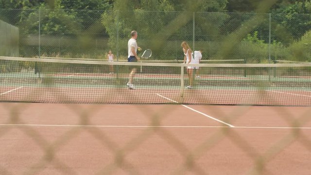 Tennis coach working with female client on outdoor court in the summer