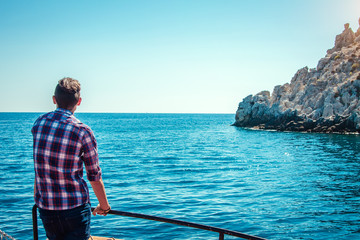 Fototapeta premium Young man enjoys the seaside view on a wooden yacht