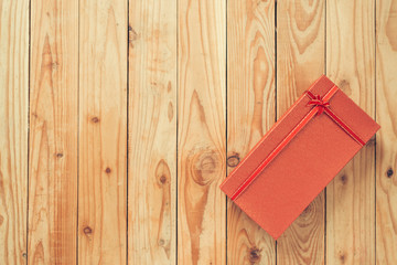 Christmas and New Year holidays gift box wrapped with red paper and yellow ribbon bow on wood table - top view on wooden table top background.